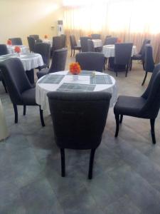 uma sala de jantar com mesas e cadeiras e uma mesa com flores em Joclarif Hotel and Suites em Zaria