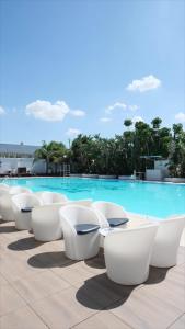 uma fila de cadeiras brancas sentadas ao lado de uma piscina em Mare Hotel em Dos Hermanas