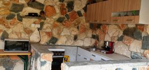 a kitchen with a stone wall with a stove and a microwave at Casa Ruby in Mangalia