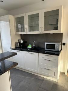 a kitchen with white cabinets and a microwave at Apartmenthaus Hamburg Les Jardins in Hamburg