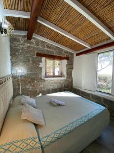 een groot bed in een kamer met een stenen muur bij Sa Domu De Orrì al Mare in Tortolì