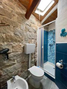 een badkamer met stenen muren, een toilet en een douche bij Sa Domu De Orrì al Mare in Tortolì