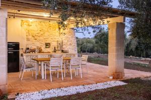 a patio with a table and chairs and a kitchen at Trullo Cinderella mit Mountainbike & Pool in Martina Franca
