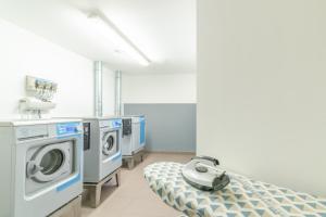 ein Krankenhauszimmer mit einer Waschmaschine und einem Bett in der Unterkunft Montempô Apparthôtel Paris-Vélizy in Vélizy-Villacoublay