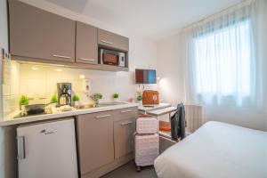 a small room with a kitchen and a bed at Montempô Apparthôtel Paris-Vélizy in Vélizy-Villacoublay