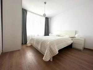 a white bedroom with a bed and a window at Carolina Residence in Alba Iulia