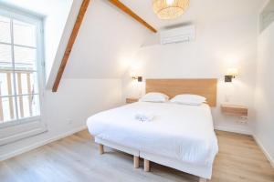 a white bedroom with a large bed and a window at Le cosy pad in Amboise