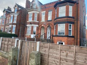 a large red brick house with a wooden fence at Pass the Keys Lovely 2 bedroom apartment in Manchester in Manchester