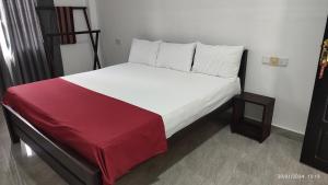 Ce lit se trouve dans un dortoir doté d'une couverture rouge. dans l'établissement Laxsume Guest House Nilaveli, à Nilaveli