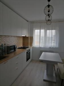 a kitchen with white cabinets and a table in it at Luxury 4-rooms, 2-bathrooms, Obor area in Bucharest