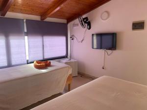 een slaapkamer met 2 bedden en een tv aan de muur bij Aparthotel Praia Baixo in São Tiago
