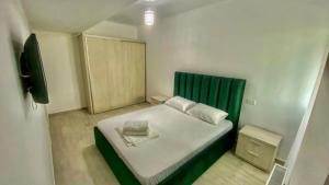 um pequeno quarto com uma cama com uma cabeceira verde em Aqua Apartament Mamaia em Mamaia