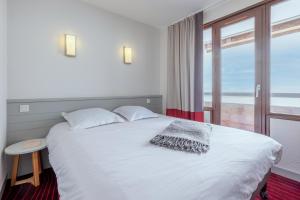 a bedroom with a white bed with a large window at Résidence Pierre & Vacances Antarès in Avoriaz