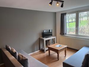 - un salon avec un canapé, une télévision et une table dans l'établissement Gasterij Berg en Dal, à Slenaken