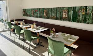 a dining room with two tables and green chairs at Hotel Oase in Bad Ischl