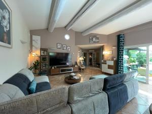 a living room with a large couch and a television at Villa d Agathe en Provence Graveson in Graveson