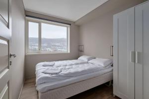 a bed in a room with a large window at Sentrumsnær og Romslig 4-roms Leilighet in Bergen