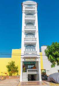 un edificio blanco alto con una torre de reloj en Khách Sạn Nhà Đất en Ấp Bình Hưng