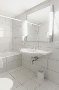 ein weißes Badezimmer mit einem Waschbecken und einem Spiegel in der Unterkunft ROESLI Guest House in Luzern
