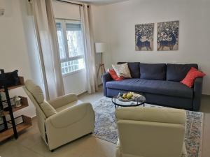 a living room with a blue couch and a chair at Heart of Baka in Meqor H̱ayyim