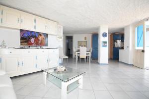 a large kitchen with white cabinets and a table at appartamento sulla spiaggia 1 in Olbia