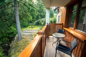 a porch with two chairs and a table on it at Malina Resort & SPA in Szklarska Poręba