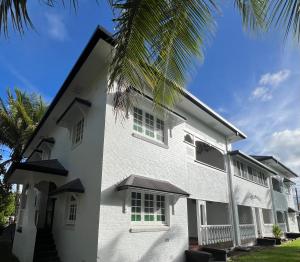 a white building with green windows and a palm tree at Sans Souci Apartments in Ingham