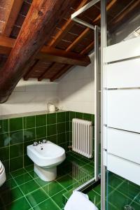 La salle de bains est pourvue de carrelage vert, de toilettes et d'un lavabo. dans l'établissement L’Abbaino, à Vicence