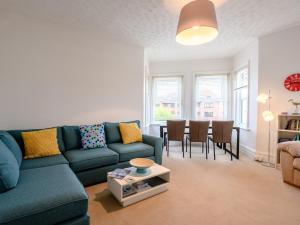 ein Wohnzimmer mit einem blauen Sofa und einem Tisch in der Unterkunft 4 Bed in Bournemouth 78807 in Bournemouth