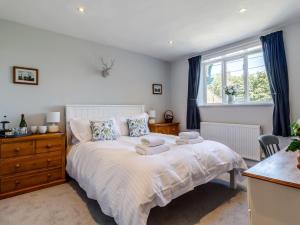 a bedroom with a bed with blue curtains and a window at 3 Bed in Syderstone 78973 in Syderstone