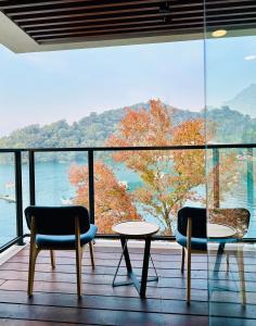 Duas cadeiras e uma mesa numa varanda com vista em 水秀一方Sun Moon Lakeside Boutique Hotel em Yuchi
