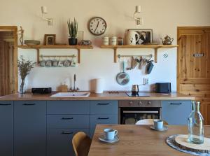 a kitchen with a table and a clock on the wall at Wooden house and modern container in Lekneno, near Zagreb in Lekneno