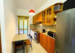 a kitchen with wooden cabinets and a table and a refrigerator at Il Giardino Di Maria - Metro C in Rome