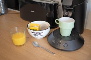 a coffee maker with a cup of orange juice and a glass at Les appartements de l'horloge in Carcassonne