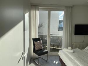 um quarto com uma cama e uma cadeira em frente a uma janela em strandnahe FeWo mit Schwimmbad im Haus, a cappella 03, Binz em Binz