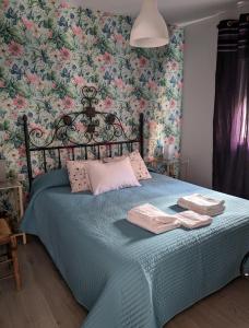 1 dormitorio con cama azul y papel pintado con motivos florales en Apartamento Turístico Monteceli, en Gata
