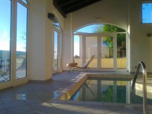 a swimming pool in a house with a chair next to it at Poggio d'Incanto in Bettola