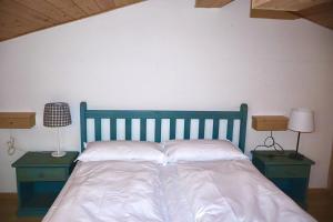 a blue bed with two nightstands and two lamps at Fiemme Village in Bellamonte