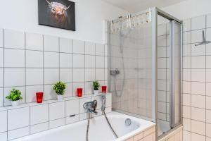 een badkamer met een bad en een douche met potplanten bij Ferienwohnung Joanna in Wolfach