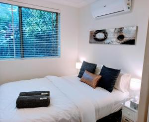 a bedroom with a white bed and a window at Palm Garden Villa-Apt - Tropical Oasis at Cronulla Beach in Cronulla