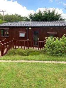 uma pequena casa com uma cerca de madeira no quintal em Lakeside retreat - Lodge 2F caer beris holiday park em Builth Wells