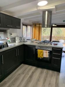 a kitchen with black cabinets and a stove top oven at Lakeside retreat - Lodge 2F caer beris holiday park in Builth Wells