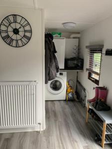 um quarto com uma máquina de lavar roupa e um relógio na parede em Lakeside retreat - Lodge 2F caer beris holiday park em Builth Wells