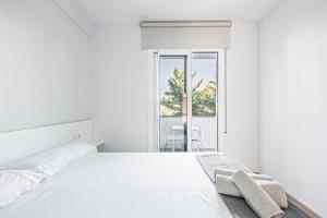 een witte slaapkamer met een bed met twee handdoeken erop bij Tango in Sitges