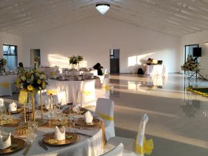 un salón de banquetes con mesas blancas y sillas blancas en Hole In One, en Roodepoort