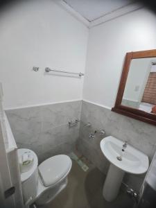 a bathroom with a toilet and a sink and a mirror at Room-Cola Inn in Siquijor