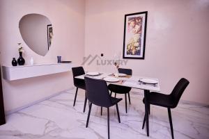 a dining room with a white table and black chairs at Luxury Suites in Parakou