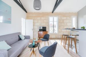 a living room with a couch and chairs and a kitchen at Magnifiques Appartements Climatises En Plein Coeur Des Chartrons in Bordeaux