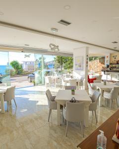 un restaurante con mesas y sillas y vistas al océano en Hotel Iliria en Sarandë