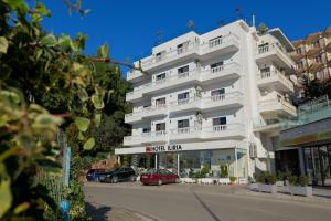 a white building with cars parked in front of it at Hotel Iliria in Sarandë